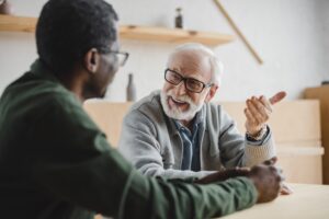 senior man talking to his african american friend at cafe